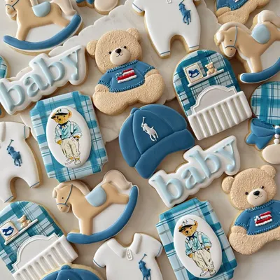 Polo-inspired baby shower cookie set in blue and white with teddy bears, rocking horses, a crib, polo-player onesies, and a baby cap with the polo pony logo.