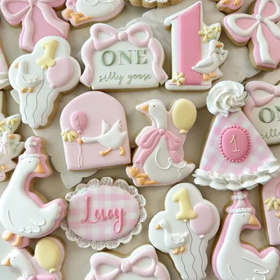 "One Silly Goose" first birthday cookie set for "Lucy" with goose characters holding balloons, a party hat, bows, and pink gingham plaques.